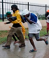 Några människor springer för att ta skydd i Jamaicas huvudstad Kingston. Foto: Anders Leighton/AP Photo/Scanpix