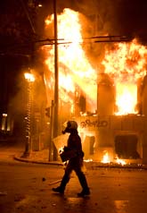 En grekisk polis utanför ett brinnande hus i Aten. Foto: Petros Giannakouris/Scanpix.