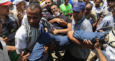 En skadad man får hjälp av sina kamrater. Militärerna sköt och dödade många demonstranter i Egypten i helgen. Foto: AP/Scanpix.