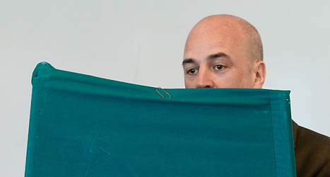 Statsminister Fredrik Reinfeldt står bakom en skärm och gör i ordning sin röst. Han är en av många svenskar som röstat i EU-valet. Foto: TT