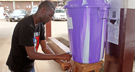 En man i staden Freetown i Sierra Leone tvättar sina händer noggrant. Alla måste vara försiktiga för att inte få sjukdomen ebola. Foto: Youssouf Bah, AP/TT. 