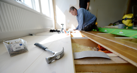 En snickare jobbar med golvet i ett hus