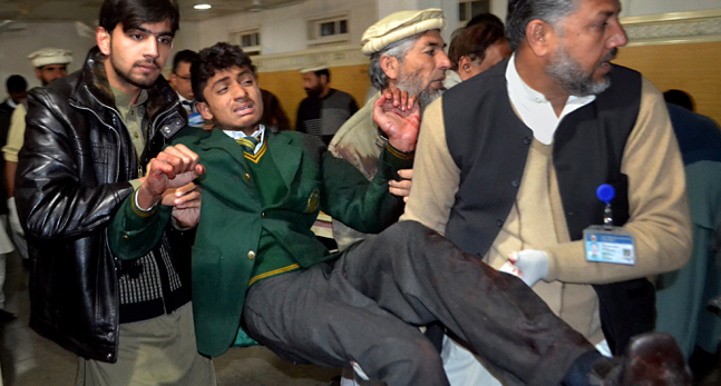 En skadad elev bärs ut från skolan i Peshawar.