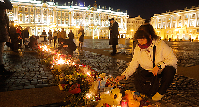 Kvinna lägger blommor vid en minnesplats i Sankt Petersburg.