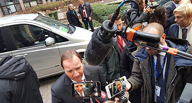 Stefan Löfven går mellan journalister med mikrofoner.