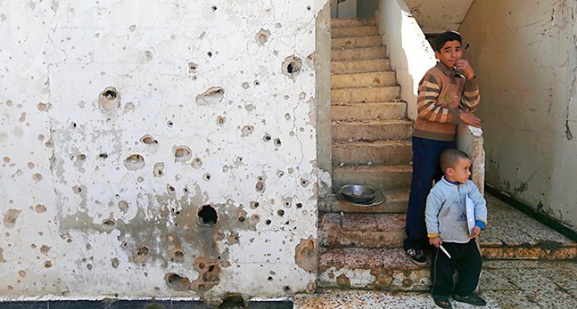 Pojkar vid ett hus i Homs i Syrien.