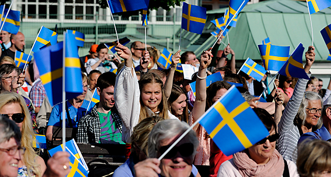 Människor viftar med svenska flaggor