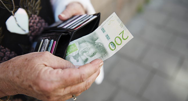 En hand håller i en plånbok och en 200kronorsedel.