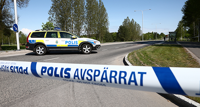 En bild på en polisbild och ett band som används för att spärra av en väg.