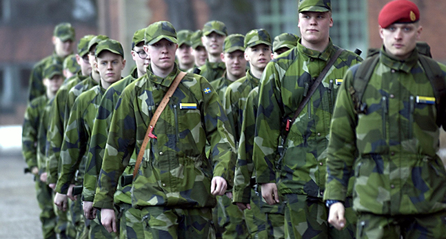 Några unga personer i gröna kläder som går på rad.