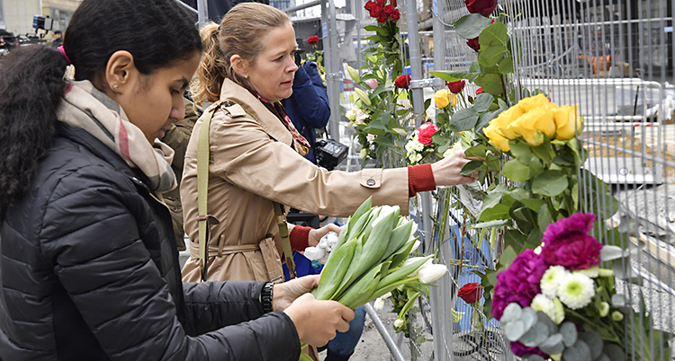 En kvinna hänger blommor på ett staket