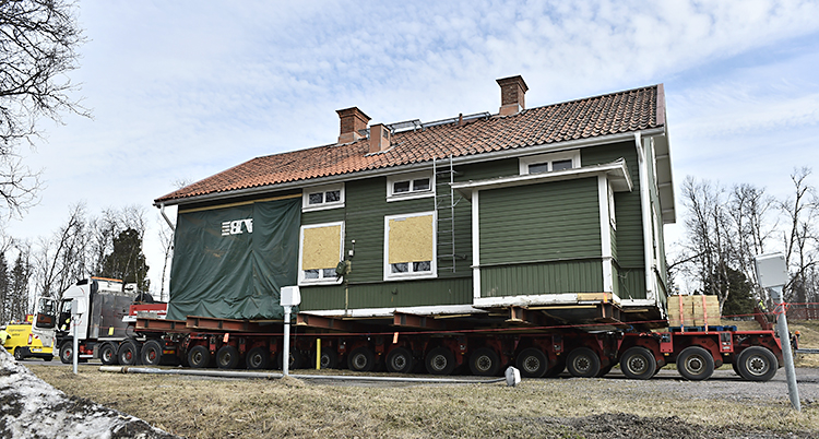 Ett stort grönt hus på ett flak till en lastbil