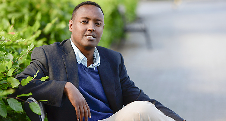 Ahmed Abdirahman sitter på en bänk utomhus.