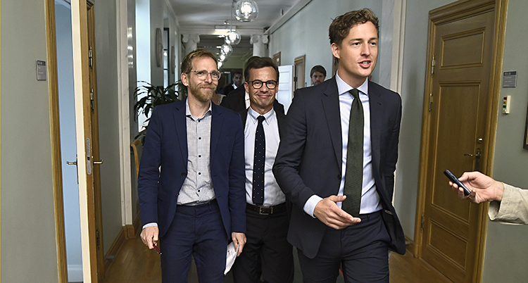 De tre politikerna går i en korridor.