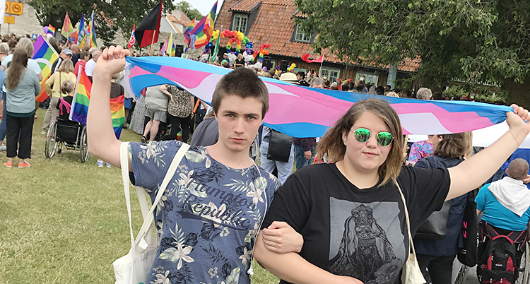 De står med en rosa flagga framför en samling av männsikor