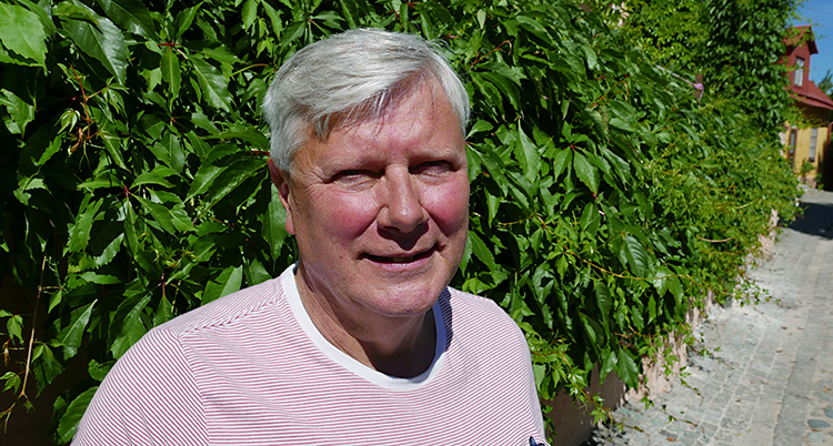 Lars Ohly står framför en mur med växter