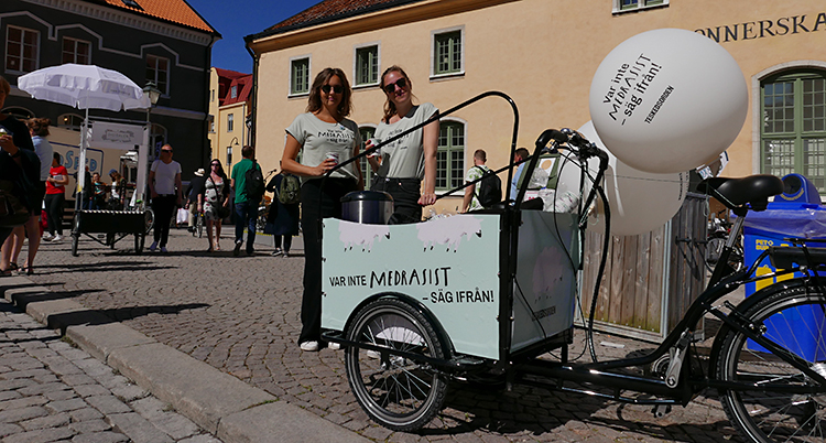 De står framför en cykelkärra med texten: Bli inte medrasist