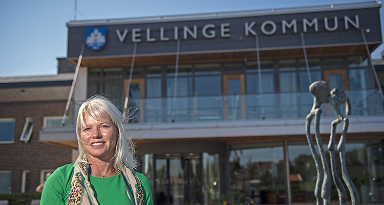 Kommunens ledare Carina Wutzler står framför kommunhuset i Vellinge. Hon har grönt på sig och ler.
