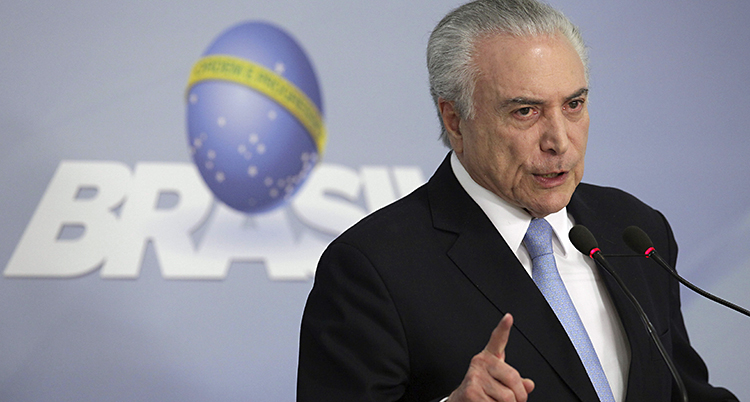 Michel Temer lyfter ett varnande finger. Han står och pratar med någon och ser allvarlig ut.