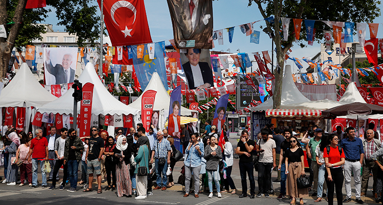 Folk på en gata i Istanbul. Gatan är fylld med tält och flaggor inför valet.