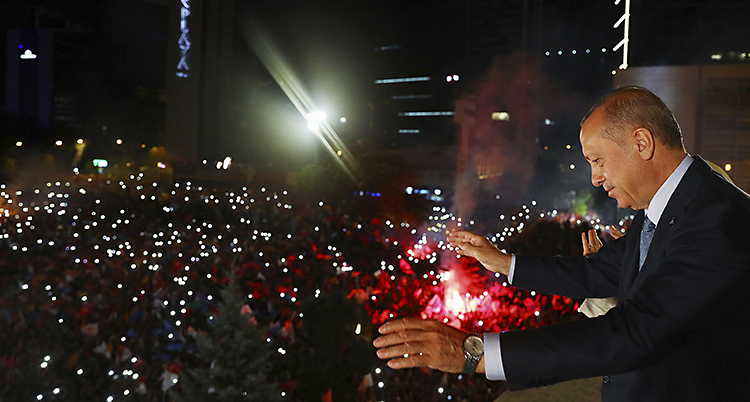 Turkiets president Erdogan står på en balkong och vinkar till människor nedanför.