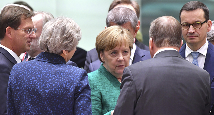 Angela Merkel står och pratar med Theresa May och Stefan Löfven.
