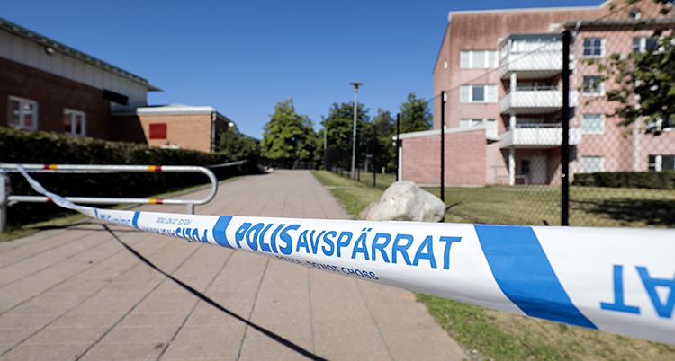En gata vid ett bostadsområde är avspärrad av polisband.