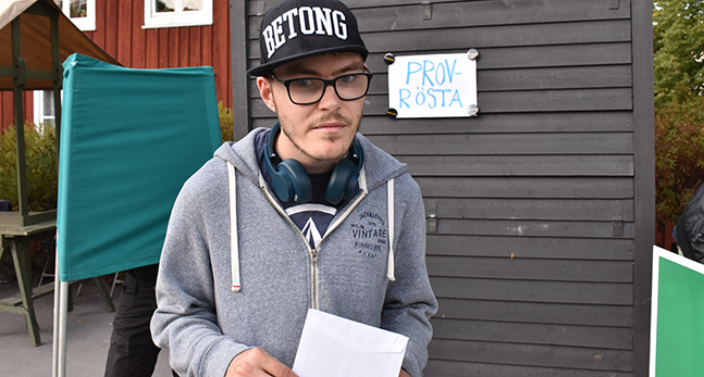 Douglas Falkenberg står utomhus med ett kuvert i handen.