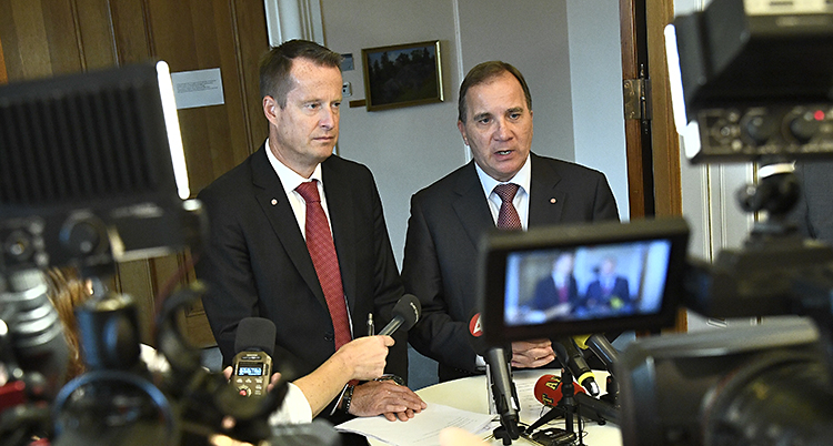 Två allvarliga män står och svarar på frågor