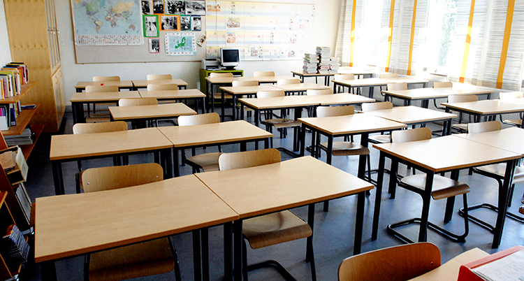 Bänkar står i rader i ett tomt klassrum