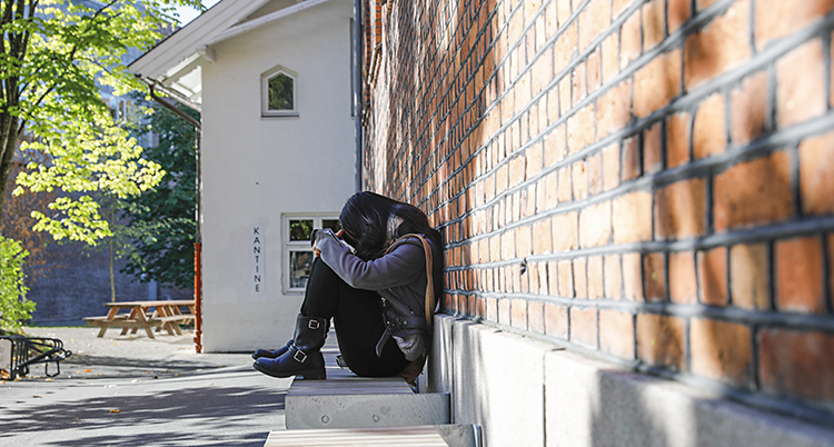 En flicka sitter ensam på skolgården