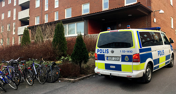 En polisbil utanför ett lägenhetshus.