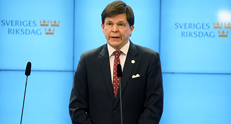 Talmannen framför en vägg där det står Sveriges Riksdag.