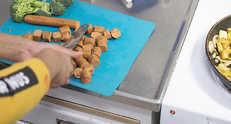 En person skär i vegetarisk korv