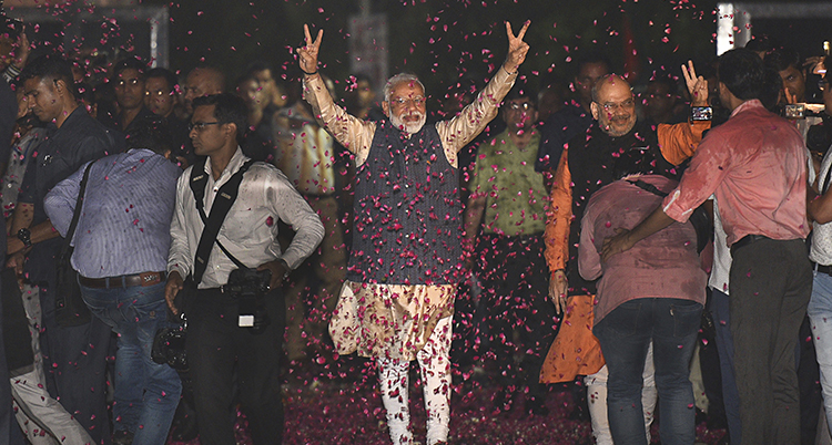 Narendra Modi sträcker händerna i luften. Röda blad faller runtomkring.