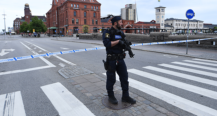 En polis med vapen stor på en gata utanför stationen