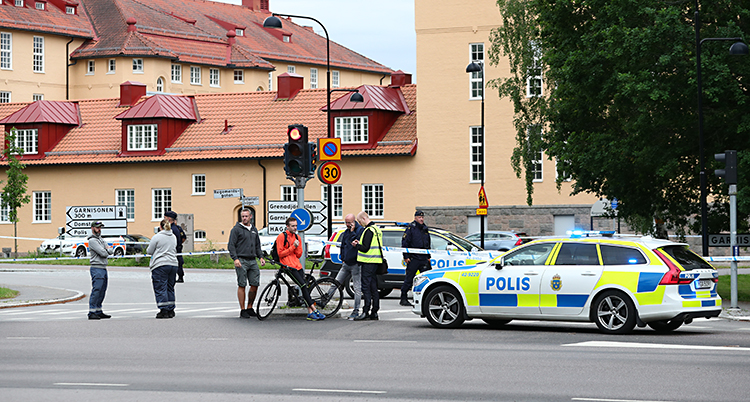 Polisbilar står i en gatan och stoppar människor
