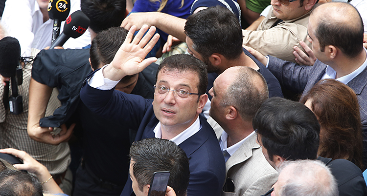 Politikern Ekrem Imamoglu står bland folk och vinkar.