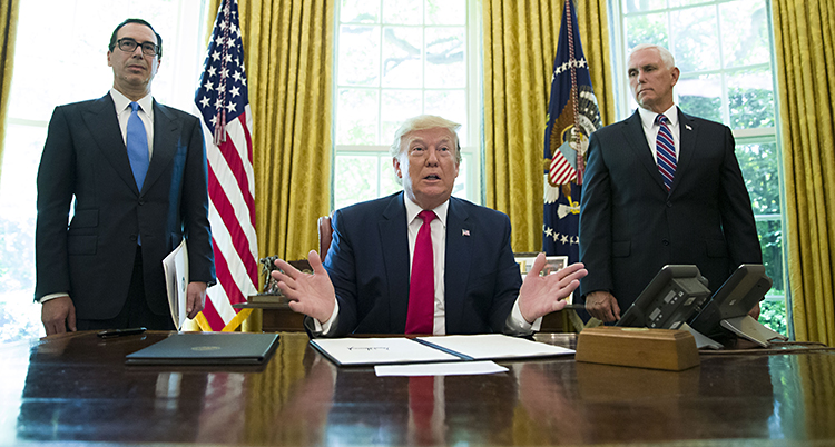 USAs president sitter bakom sitt skrivbord. På varsin sida har han en medhjälpare.
