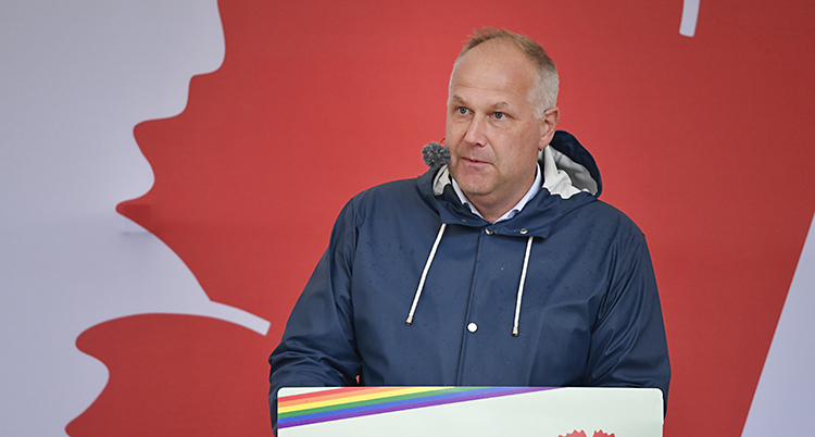 Jonas Sjöstedt står med regnjacka och håller ett tal på en scen.
