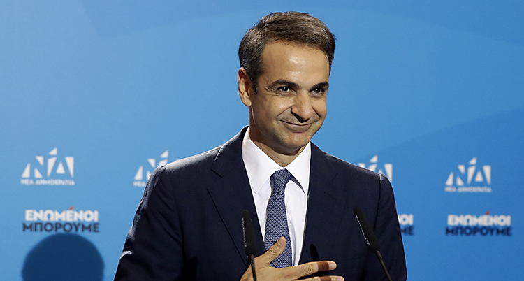 Kyriakos Mitsotakis i mörk kostym ler mot publiken (som vi inte ser)