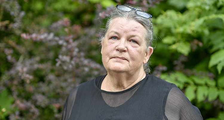 Elisabet Nilsson står med svarta kläder. I bakgrunden syns träd och blad.