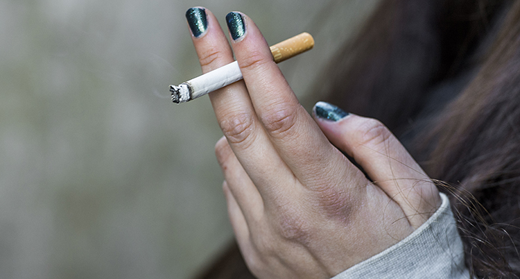 En hand med grönt nagellack håller en cigarett
