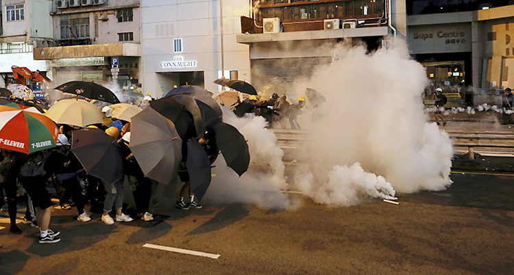 Människor håller fram paraplyn. Vit rök kommer mot dem.