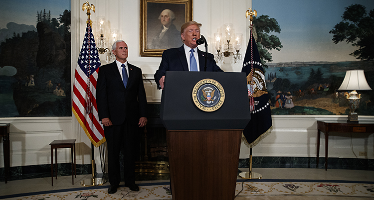 Donald Trump står i en talarstol med flaggor på båda sidorna.
