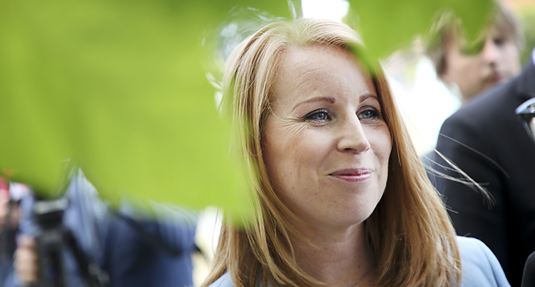 Närbild på Annie Lööf. Hon ler och står nära ett träd.