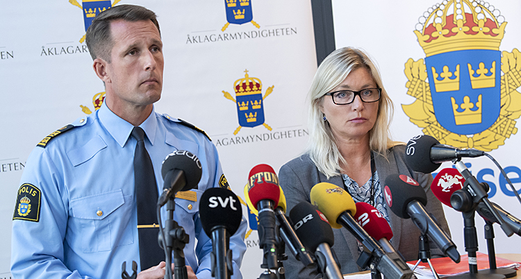 Två personer står framför många mikrofoner.