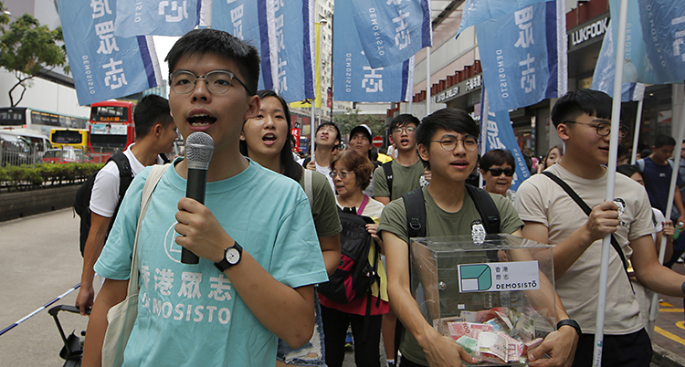 Joshua Wong står framför många människor och talar i en mikrofon.