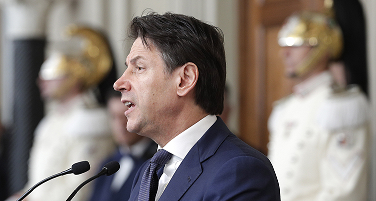 Guiseppe Conti klädd i blå kostym och slips fotad i profil framför en mikrofon.