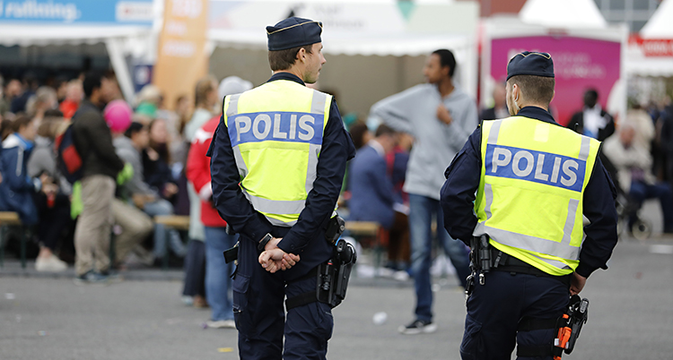 En polis med gul polisväst står på gatan.